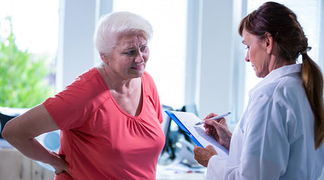 elderly mature woman in doctor's office showing signs of back pain. buy cbd roll on for pain. How often can you use cbd roll on for pain?